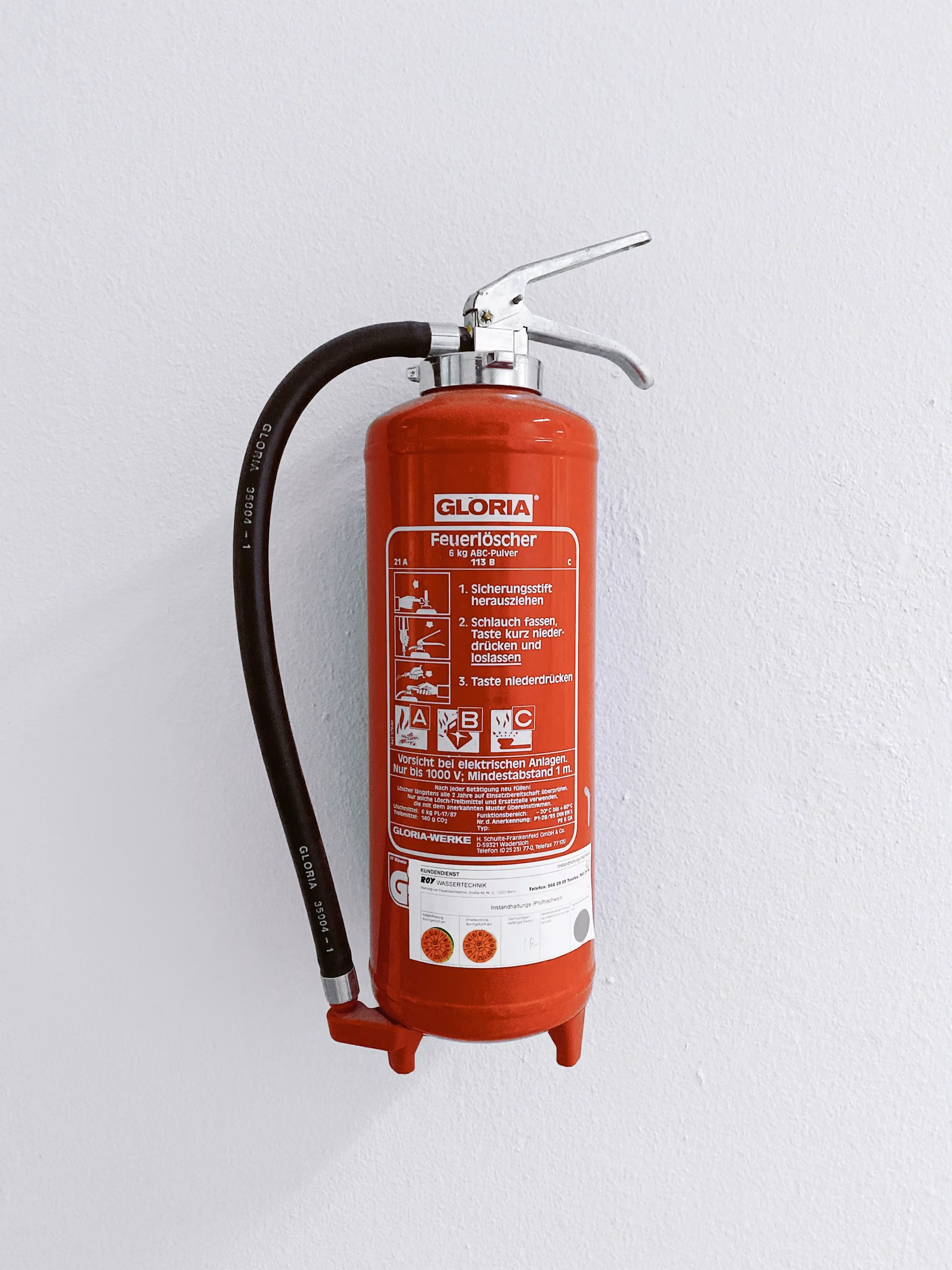 Extincteur rouge fixé à un mur blanc